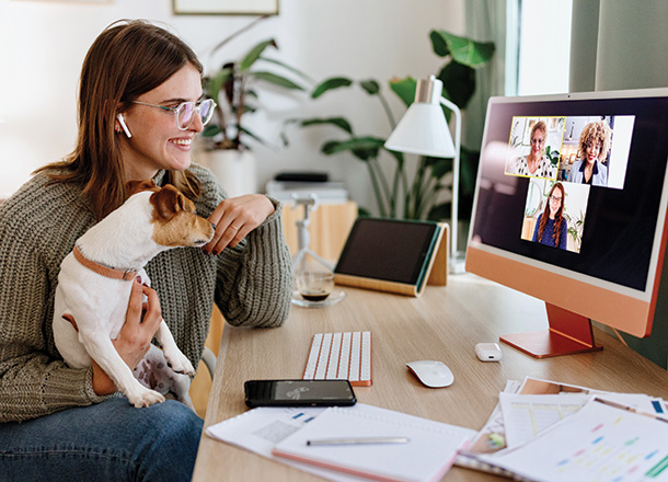 Staff working from home holding her dog on a computer video call with a seamless connection.