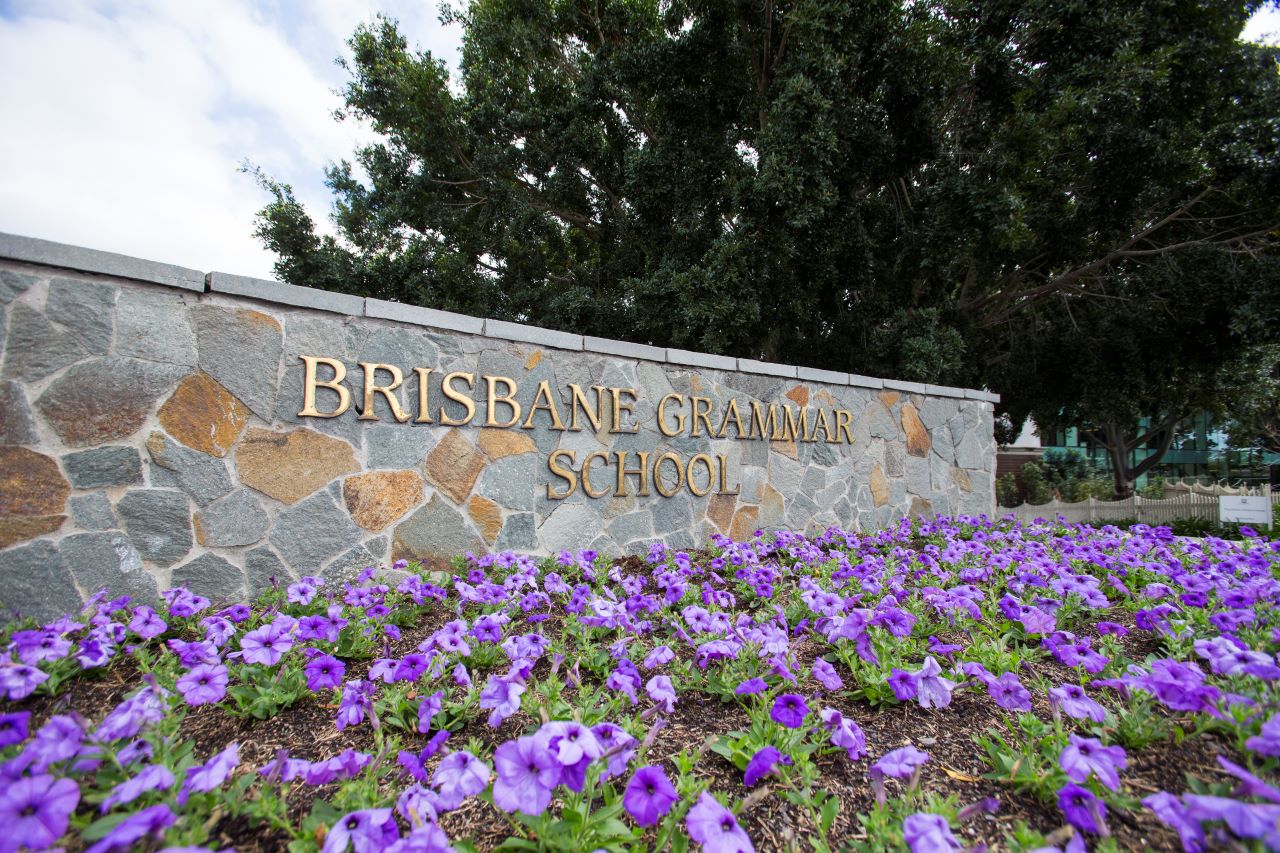 Brisbane Grammar School sign with purple flowers in front