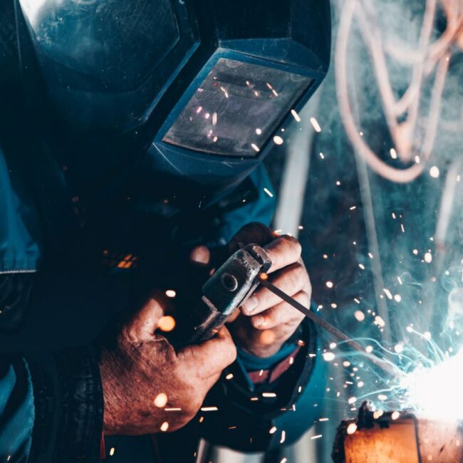 Man wearing safety gear welding metal