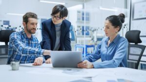 3 people sitting around a laptop